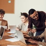 A diverse group of professionals engaged in a collaborative office meeting, sharing ideas and discussing projects.